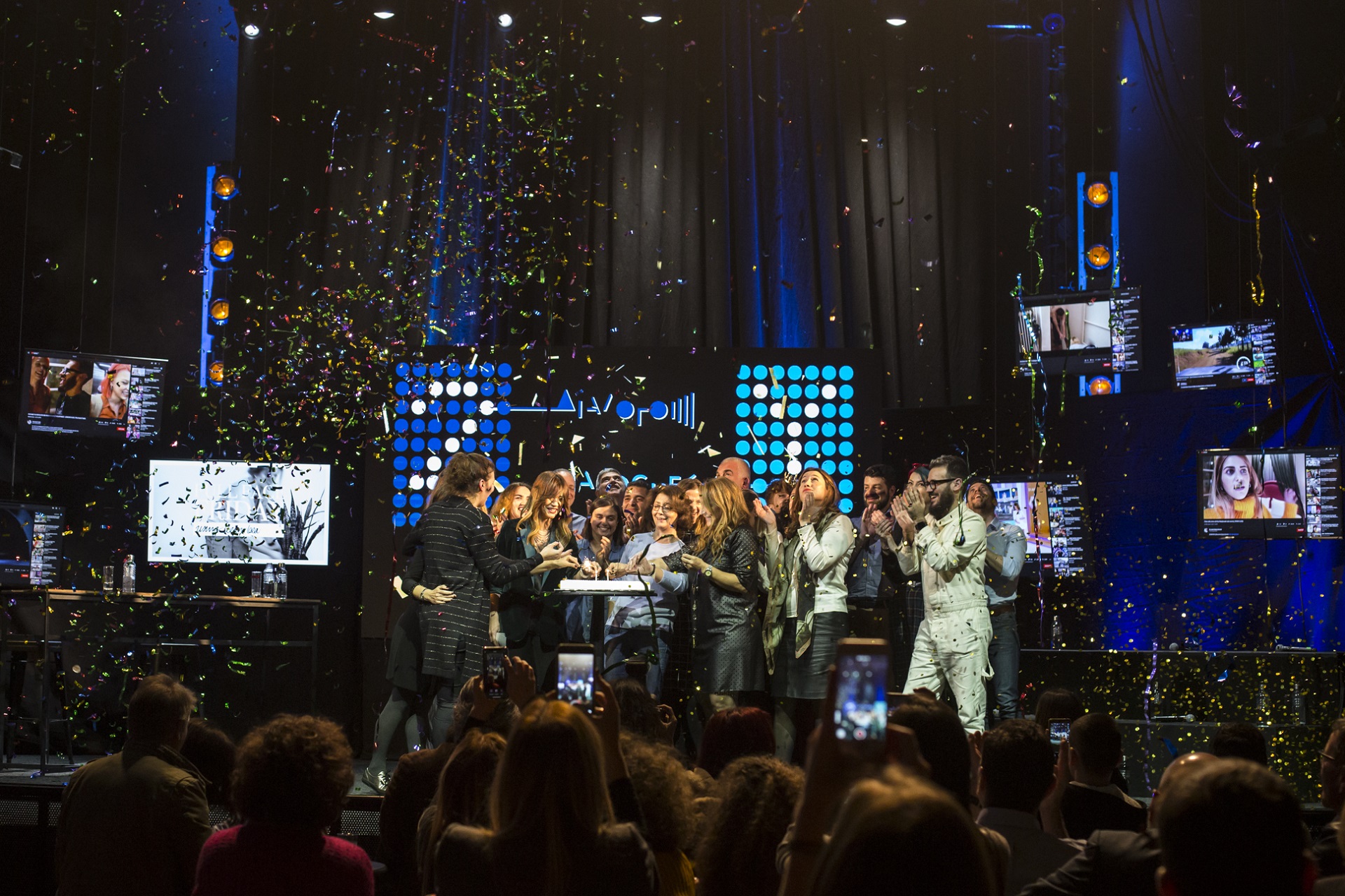 Όλοι οι συμμετέχοντες ομιλητές στη σκηνή ανάβουν κεριά σε μια τούρτα με κομφετί να πέφτει στη συζήτηση των Διαλόγων ΙΣΝ.