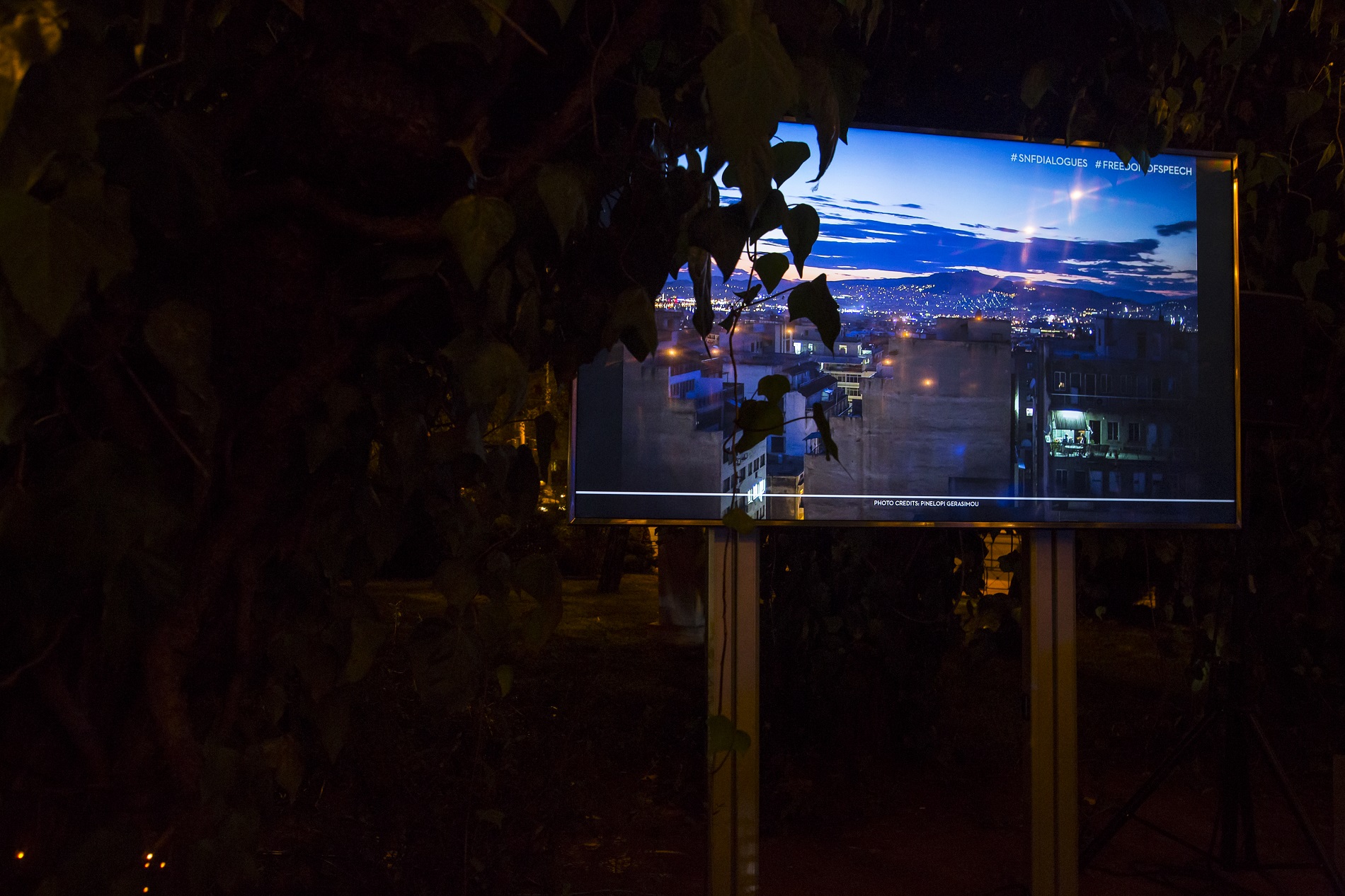  A large screen on a stand in the dark, displaying vibrant colors and sharp urban images.