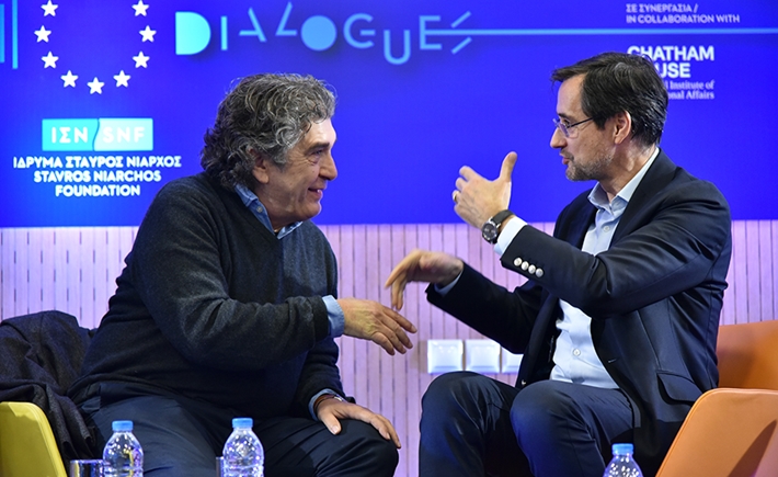 Two guests discussing with each other at the SNF Dialogues event in front of a bold background