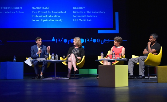 Four speakers sitting on chairs on the stage at the SNF Dialogues event.
