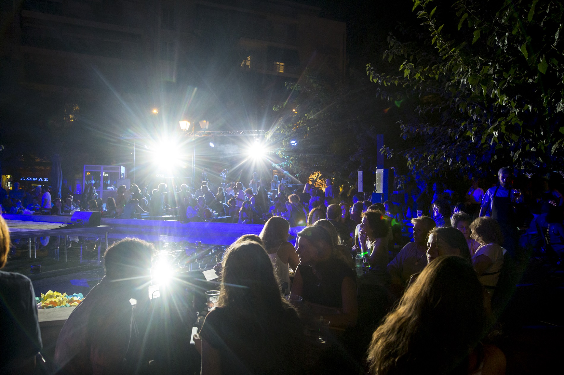 A stage in the background and a crowd of people in the foreground at night at the SNF Dialogues event.