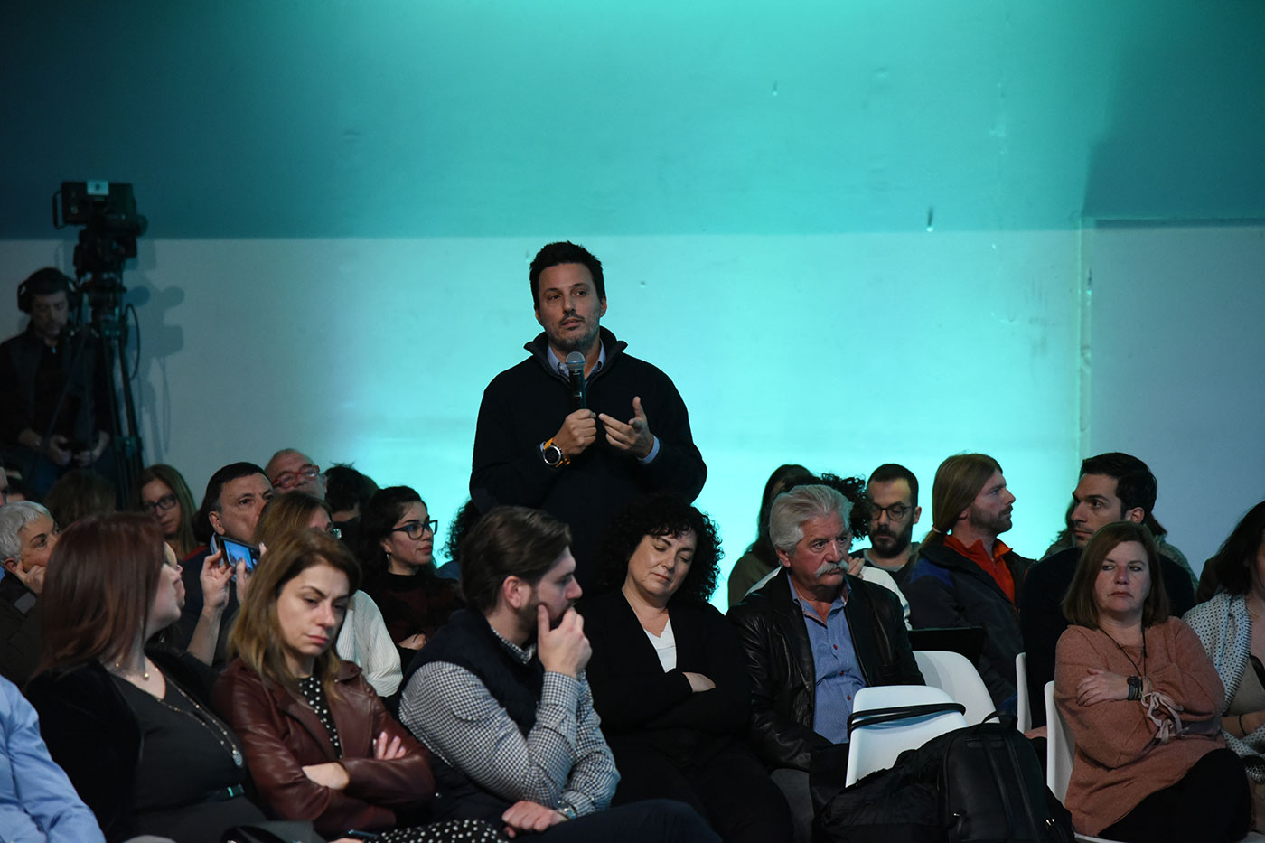 A man from the crowd standing and speaking into the microphone at the SNF Dialogues event