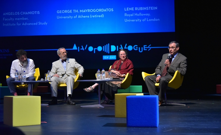 Four speakers sitting on chairs on the stage at the SNF Dialogues event.