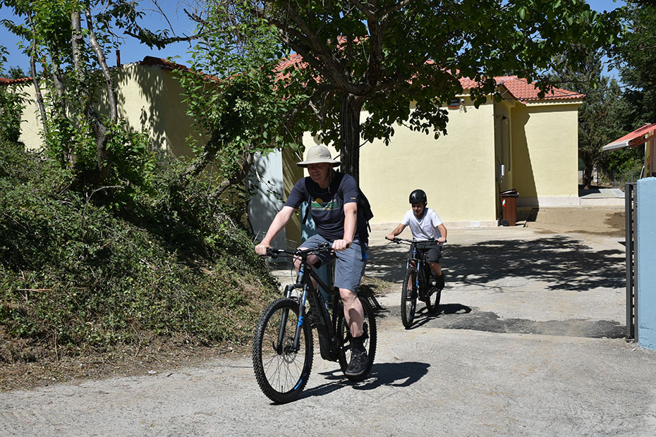Ένας ηλικιωμένος άνδρας και ένα παιδί κάνουν ποδήλατο στους δρόμους του χωριού 