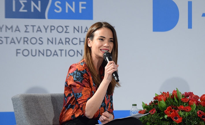 Anna Kynthia Bousdoukou smiling holding a mic and speaking at the SNF Dialogues event.
