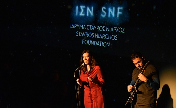 Μια γυναίκα που τραγουδάει και ένας άνδρας δίπλα της που παίζει κιθάρα πάνω στην σκηνή σε συζήτηση των Διαλόγων ΙΣΝ