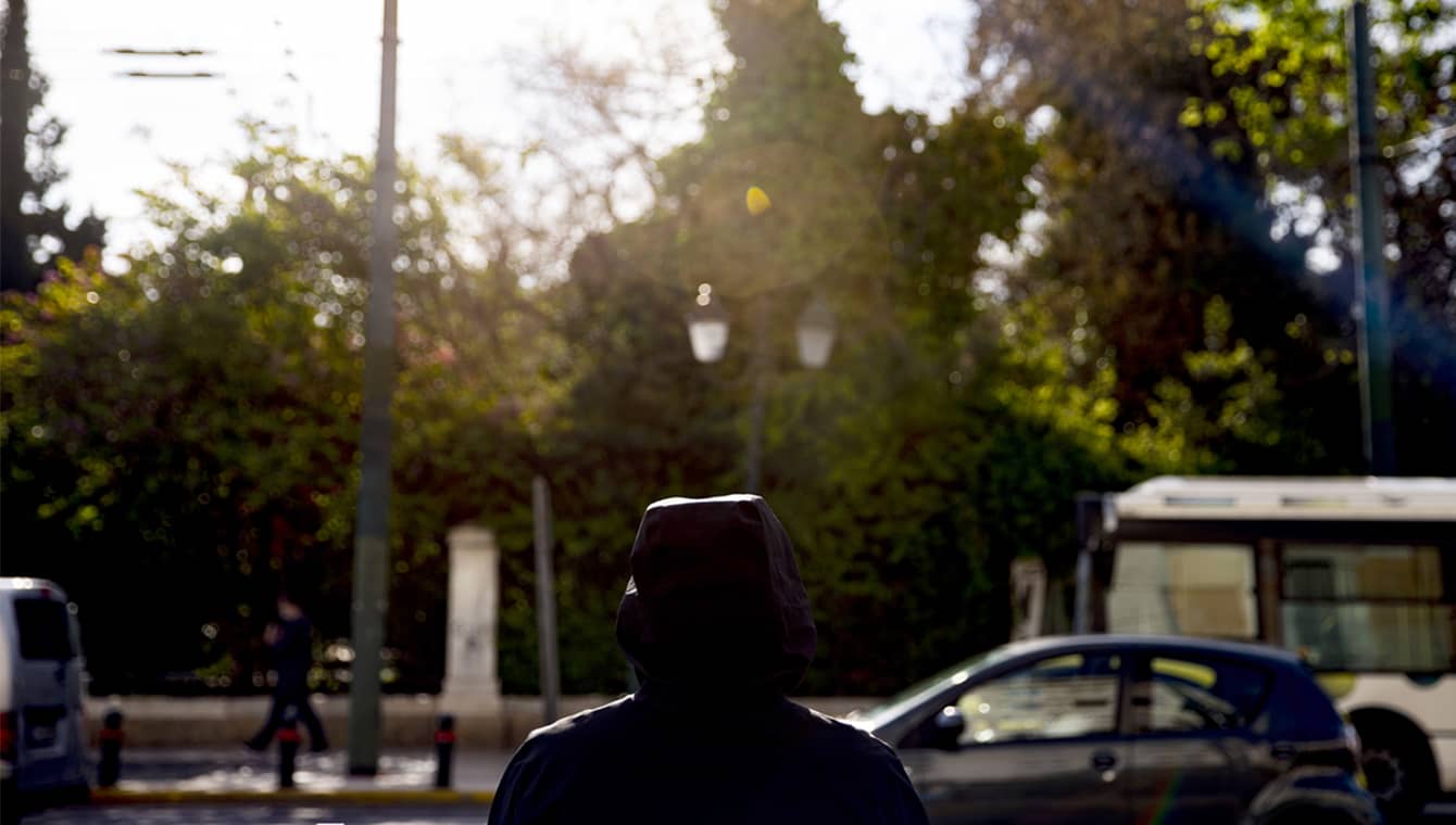 Banner showing a man from the back looking at a road with traffic and a park.