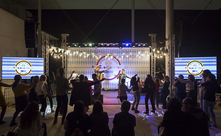 The crowd dancing in front of the stage where the musicians are playing at the SNF Dialogues event, 