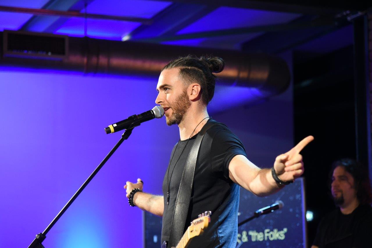 Μέλος του μουσικού γκρουπ στο μικρόφωνο με ανοιχτά χέρια.