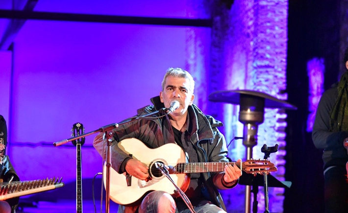 Ένας από τους μουσικούς που παίζει στη σκηνή με έντονα φώτα πίσω του