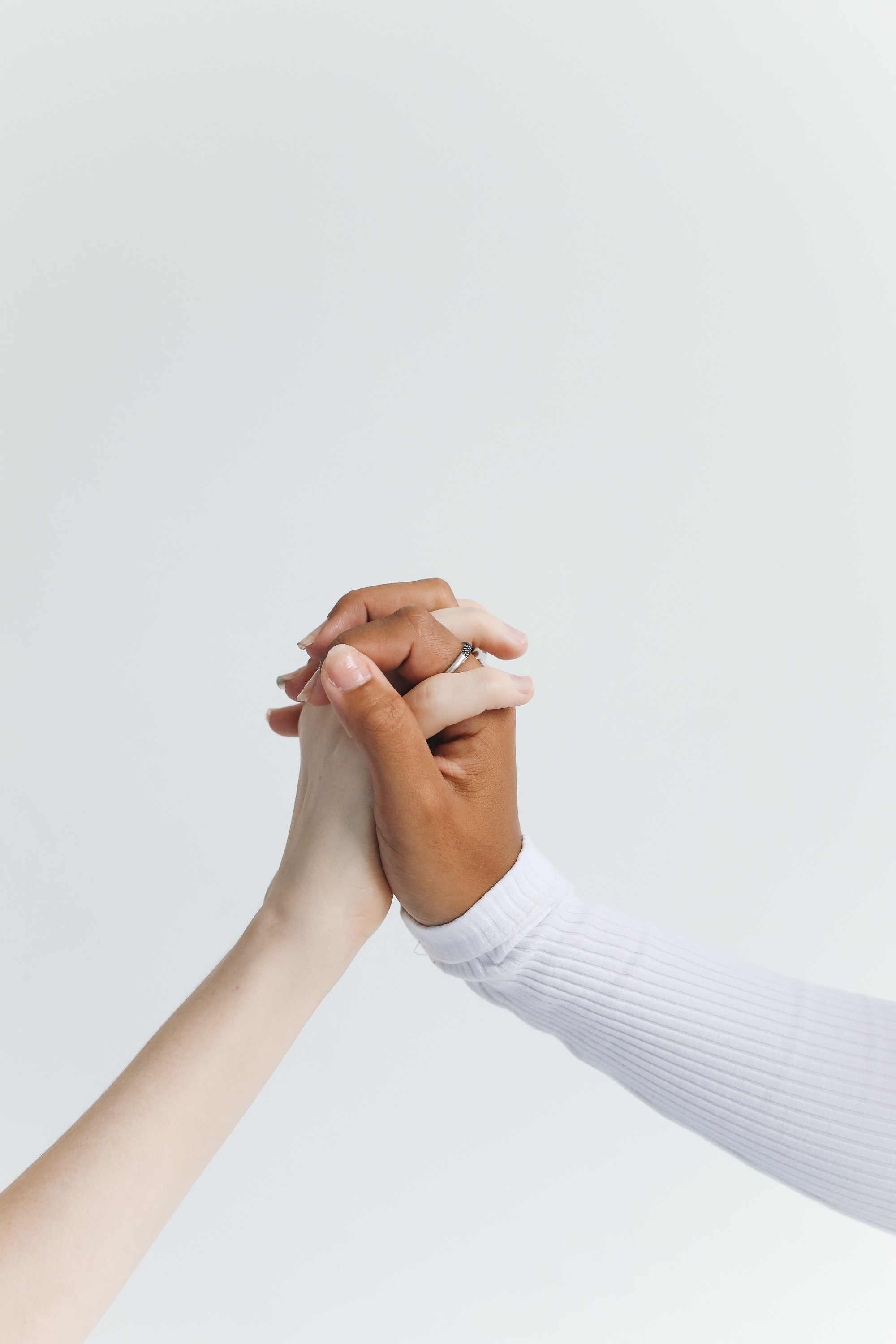 Two people of different ethnicities holding hands against a white background