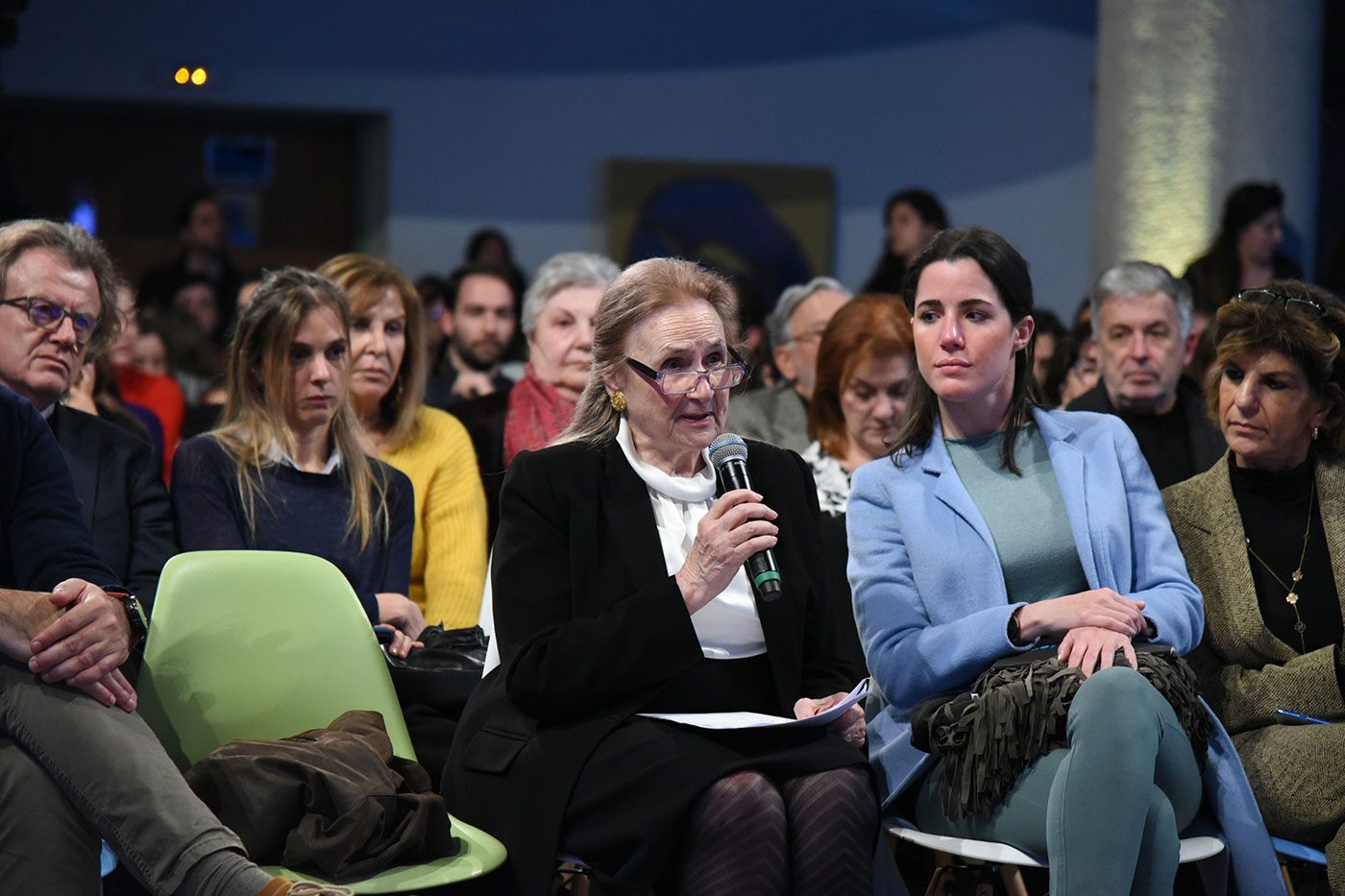 A woman from the crowd holding speaking into the microphone at the SNF Dialogues event