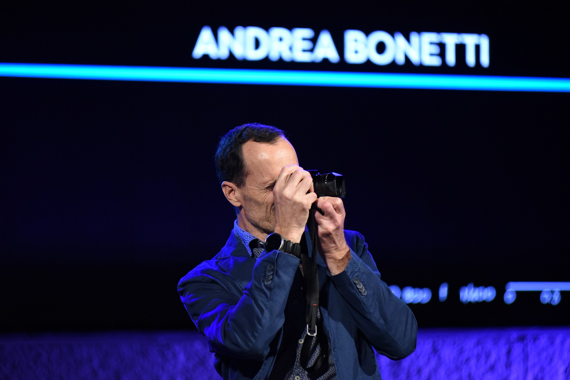 Man holding a camera at the SNF Dialogues event.