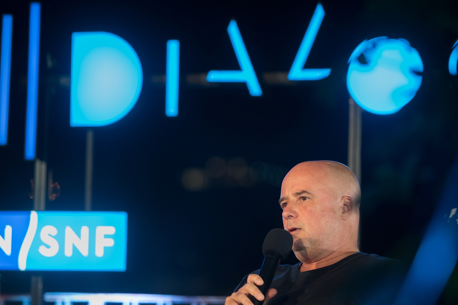 Co-president of SNF A. Drakopoulos holding the mic at the SNF Dialogues event.