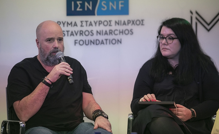 Ένας άνδρας που μιλάει στο μικρόφωνο και μια καλεσμένη δίπλα του στη συζήτηση των Διαλόγων ΙΣΝ