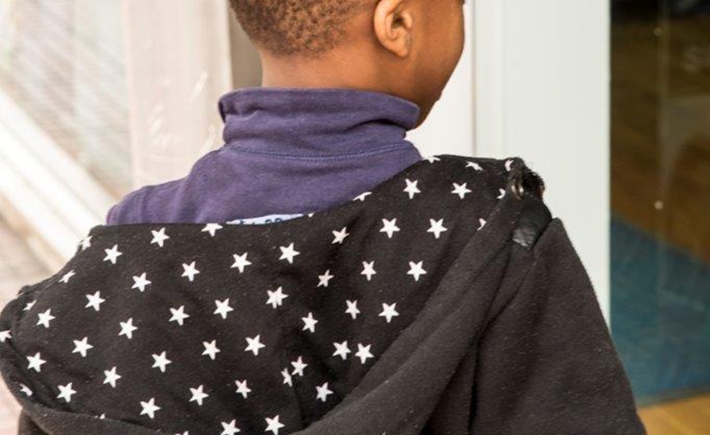 A young boy wearing a cardigan with star patterns on the hood