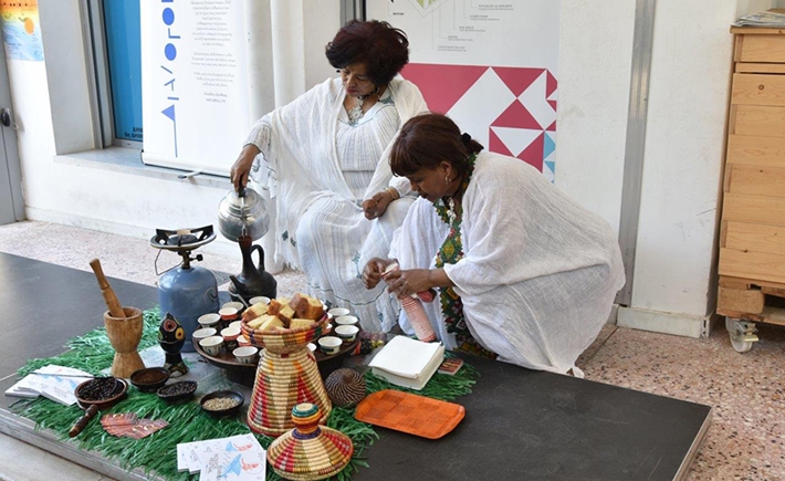 Two women in white robes making traditional African beverages 