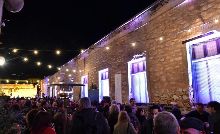 Το μεγάλο πλήθος συγκεντρωμένο έξω σε μια αυλή με έντονα φώτα από πάνω τους