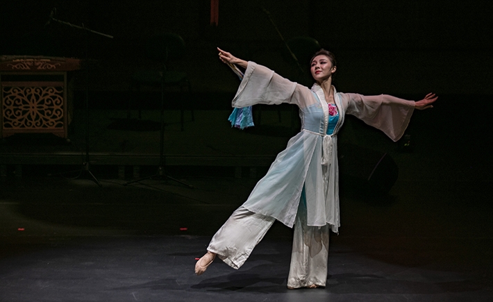 Μια γυναίκα με παραδοσιακή κινεζική φορεσιά εκτελεί παραδοσιακό χορό στη σκηνή