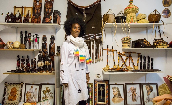 A woman in a traditional costume posing for a photo in front of African statues and art