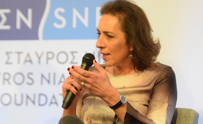 Γυναίκα ομιλήτρια κρατά ένα μικρόφωνο και μιλά στο κοινό στη συζήτηση των Διαλόγων ΙΣΝ.