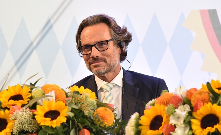 Photo of a man at the SNF Dialogues event in front of a bouquet of flowers