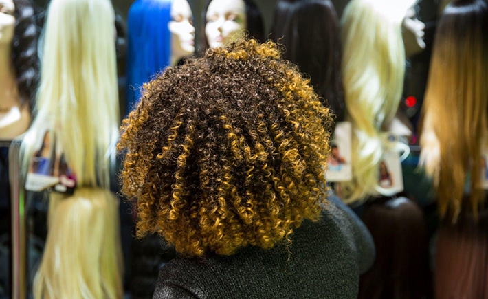 A woman with very curly and voluminous hair looking at wigs