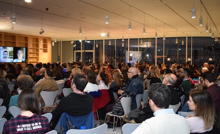 Μεγάλο κοινό φωτογραφημένο από πίσω καθισμένο σε καρέκλες σε μια αίθουσα στη συζήτηση των Διαλόγων ΙΣΝ.