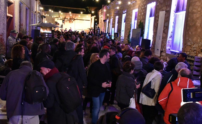 Το μεγάλο πλήθος συγκεντρωμένο έξω σε μια αυλή με έντονα φώτα από πάνω τους