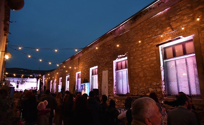 The yard of the building with bright lights and people gathered outside