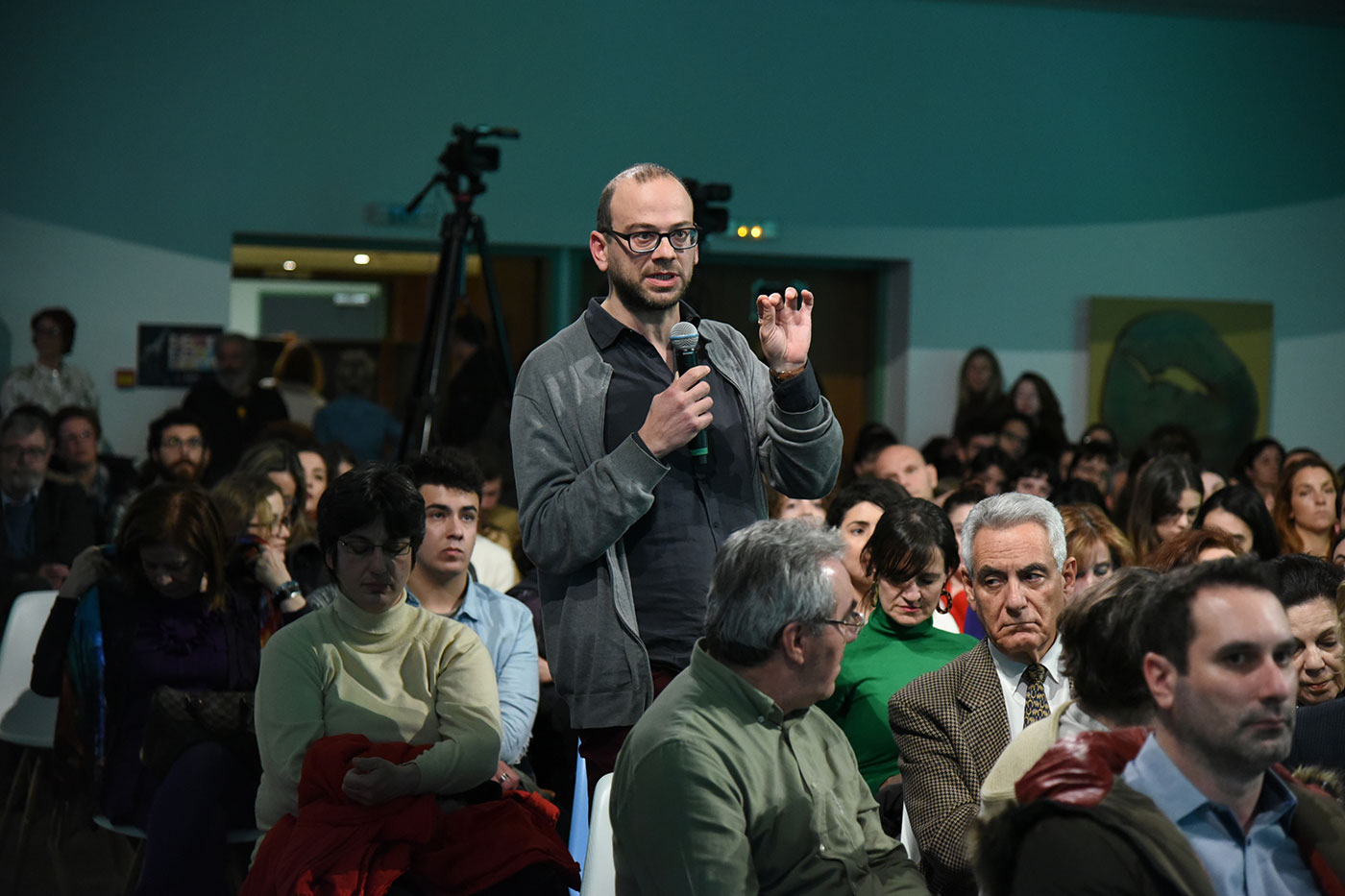 A man from the crowd standing and speaking into the microphone at the SNF Dialogues event