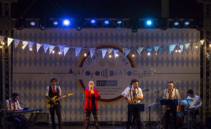 Band playing on the stage in front of a colorful background at the SNF Dialogues event