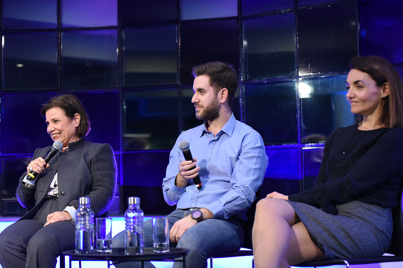 Τρεις καλεσμένοι καθιστοί με μικρόφωνα στη συζήτηση των Διαλόγων ΙΣΝ