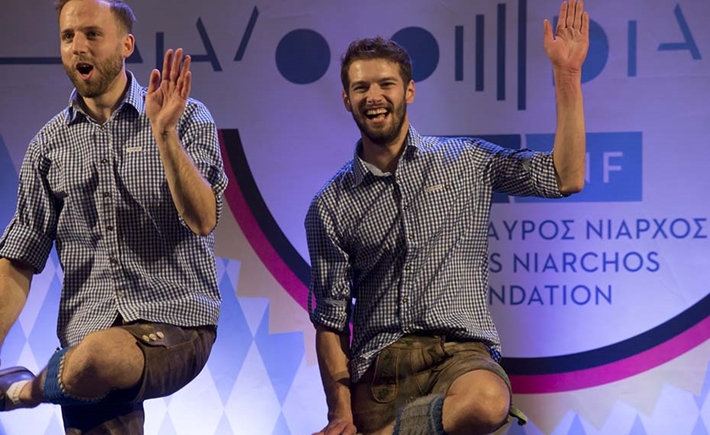 Two men dancing at the SNF Dialogues event in front of a colorful background