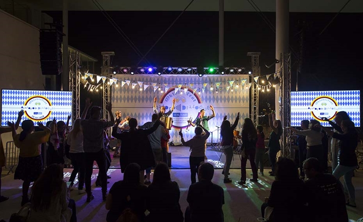The crowd dancing in front of the stage where the musicians are playing at the SNF Dialogues event, 