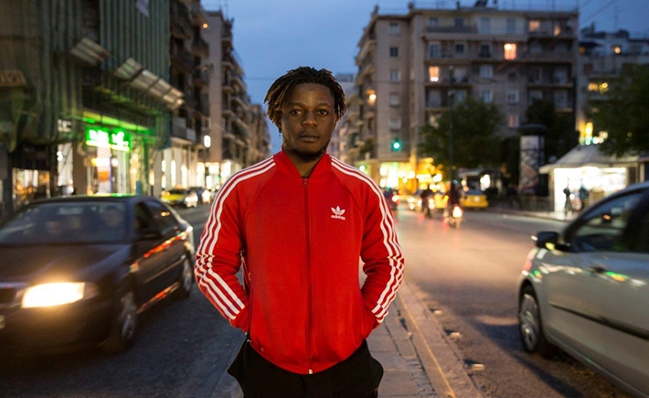 A man in a red jacket posing for a photo in the middle of a city street